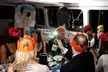 A group of people in paper crowns gathered around a table with glasses and a wine bottle inside a boat