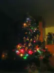 A decorated Christmas tree with colorful lights and ornaments in a dimly lit living room.