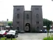 Main entrance of a historic brick building with two towers and cars in an outdoor parking area in Oslo