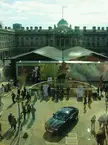 London Fashion Week crowd in an outdoor courtyard with a black BMW car and a historic building