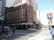 People in casual streetwear and blue denim skinny jeans crossing an urban city street by a tall brick building