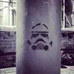 Storm Trooper graffiti stencil of a helmet spray-painted on a grey pillar in an urban setting