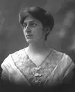 Crystal Eastman in a black and white vintage photo wearing a white dress with a lace v-neck
