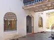 Entrance to a 16th-century religious building in India with arched windows, hanging lanterns, and shoes on stone tiles.