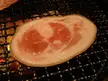 Cursed food: a slice of raw meat grilling on a metal grate over hot coals.
