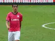 Yago González in a red Canon soccer jersey and white shorts on a green field, showing tattoos on his right arm.