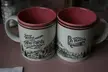 Two vintage railroad-themed ceramic mugs with pink interiors on a pink surface.