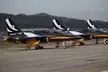 Three black and yellow ROKAF T-50 jets of the Black Eagles aerobatic team in a lineup on an airfield.