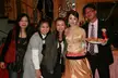 Five Chinese friends posing indoors, including a woman in a gold halter top gown and a man in a black suit.