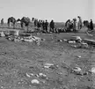 People in traditional long robes and head coverings with camels and sacks at the well at al-Khalasa
