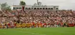 Crowd in bleachers at Richardson Memorial Stadium at Queen's University watching football players in yellow uniforms