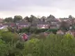 Red brick houses and green trees in Hempstead, Kent, under a cloudy sky.