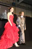 A woman in a strapless red ruffled gown and a man in a grey three-piece suit at the Salon du mariage de Luxembourg