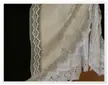 Close-up of a cream-colored dirndl fabric with white lace trim and floral embroidery
