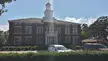 Locust Grove Institute Academic Building, a red brick City Hall with a white clock tower and parked cars