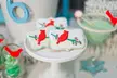 Red cardinal-themed sugar cookies on a white cake stand with a green cocktail and candies for vintage christmas photos