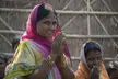 Indian woman in a pink and yellow floral print sari with hands in a prayer gesture