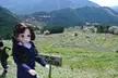 Licca-chan doll in a blue school uniform standing before the Maruyama Senmaida terraced fields and mountains