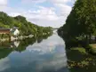 The Loire river reflecting a blue sky with white clouds, lush green trees, and white buildings in Centre-Val de Loire