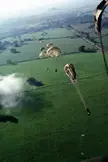 1st Bn, 508th Infantry paratroopers descending with open parachutes over a green rural landscape in Panama.