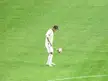 Kewell in a white athletic wear uniform juggling a soccer ball on a green grass field.