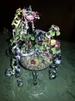 Chimney sweep figure in a top hat with a decorative houseplant in a glass bowl and colorful ribbons