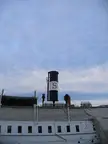 Close-up of a vintage ship smokestack with a white band and the letter 'S' against a cloudy sky.