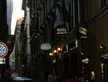 Rome, Italy street at dusk with a black BMW car, people in streetwear, and signs for Hotel Memphis and pizzerias