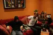 Two men on a red sofa in a living room with wall art oil painting and tattoo sleeve inspiration