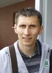 Sergiu Radu in athletic wear, wearing a striped polo and grey jacket against a brick wall.