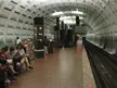 People in 2000s style streetwear, including denim shorts and baseball caps, on the Eastern Market subway platform.