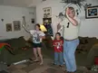 Dad playing Just Dance in a living room with a girl and boy, holding white spray bottles and wearing casual denim jeans