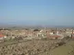 Belianes town in Urgell with terracotta roofs, dormant orchards, and distant mountains under a blue sky
