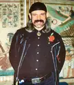 James Chalgren in 1987 wearing a black leather jacket, bandana, and blue jeans in front of Egyptian murals