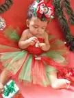 Jasmine Emily in a red and green tutu and large bow with Christmas decorations