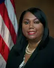 Felicia C. Adams, a plus-size Black woman with long black hair and red lipstick, wearing a pearl necklace and black blazer.