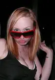 Beautiful voluptuous woman with reddish-blonde hair, red-framed sunglasses, and a black strapless dress