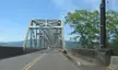 The Julia Butler Hansen Bridge, a white steel truss bridge crossing toward Puget Island with mountains in the background.