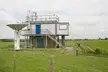 Low Frequency Array equipment rooms with a satellite dish and antennas in a grassy field