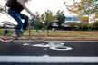 A person in blue jeans and a dark top riding a blue bicycle across a bike lane on the Eastern Mennonite University campus.