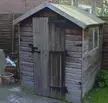 A vintage British wooden garden shed with a gabled roof and flower pots in a Lincolnshire backyard.