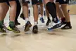 Close-up of athletes' legs, socks, and sneakers on a wooden indoor sports court