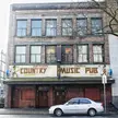 Vintage photo of a silver car parked by Vancouver's Country Music Pub in Gastown