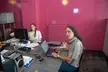 Two people with brown hair and pale skin at linux desktop setups in a room with pink walls