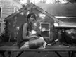 Ciara and Lily, a woman in a sleeveless shirt and shorts sitting on a wooden bench with a cute cat.
