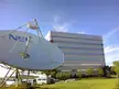 NEC office building and large satellite dish under a blue sky with BMW cars