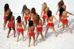 Olympic cheerleaders in red bikinis and short skirts on a white sandy beach