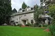 A grey two-story house with a green lawn and trees, an old vintage photo of a 1909 establishment in Oregon.