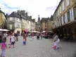 People in summer dresses and streetwear walking through the cobblestone streets of Sarlat la Caneda.