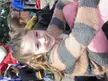 A smiling girl with brown hair and fair skin wearing a striped sweater and pink pants in a group.